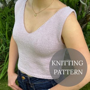 Op de afbeelding: Een lichtpaarse gebreide top met een diepe V-hals. De mouwloze top is gemaakt van zacht, getextureerd garen. De tekst "KNITTING PATTERN" staat op de afbeelding.