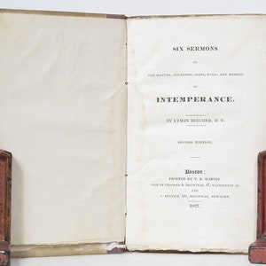 May include: A vintage book titled "Six Sermons on the Nature, Occasions, Signs, Evils, and Remedy of Intemperance" by Lyman Beecher, D.D. The book is a second edition and was printed in Boston in 1827.