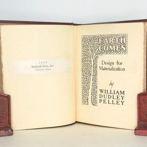 May include: A vintage book titled "Earth Comes: Design for Materialization" by William Dudley Pelley. The book cover features a decorative design of a tree with leaves and the title in a stylized font.