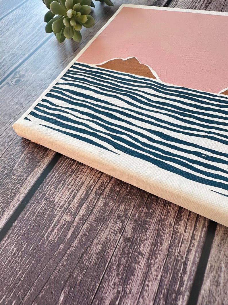 May include: A canvas painting depicting a pink sky with brown mountains above a blue and white striped sea.