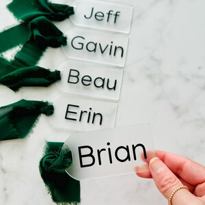 May include: Five clear acrylic place cards with black lettering. The names on the cards are Jeff, Gavin, Beau, Erin, and Brian.