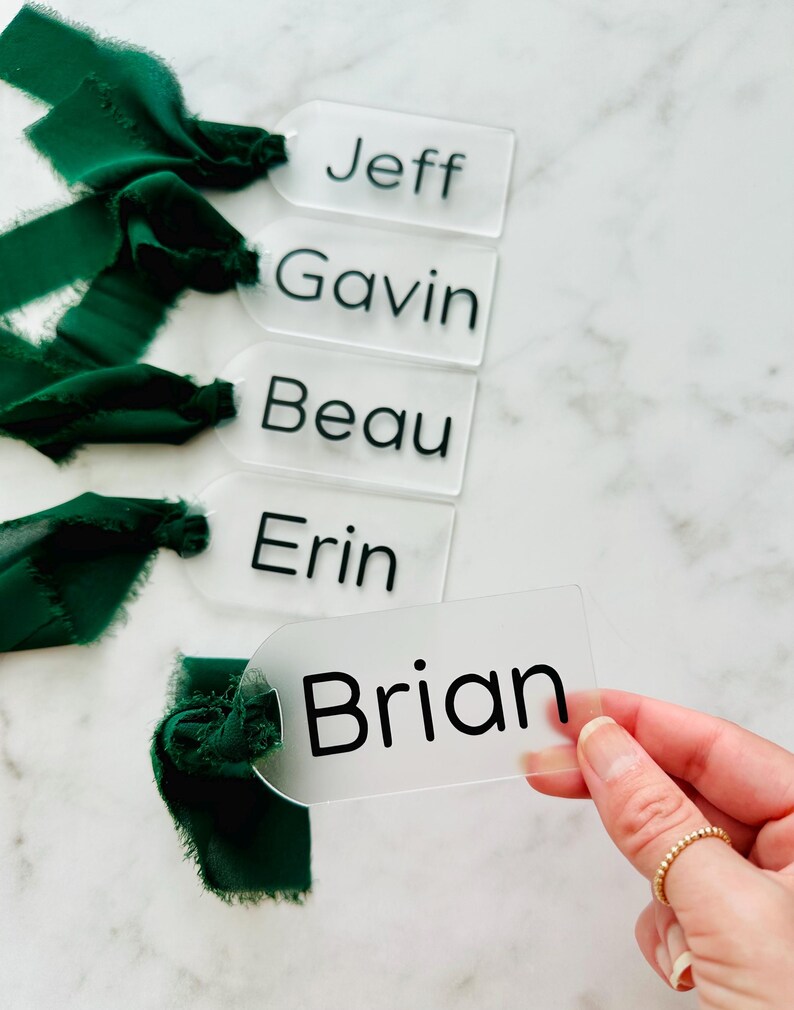 May include: Five clear acrylic place cards with black lettering. The names on the cards are Jeff, Gavin, Beau, Erin, and Brian.