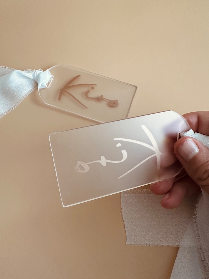 May include: Two clear acrylic gift tags with the word "Kiro" written on them in gold and white ink.