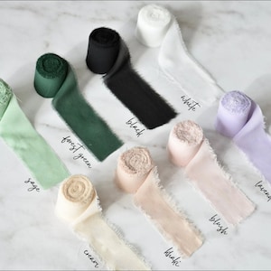 May include: Assortment of silk ribbon rolls in various colors, including sage, forest green, cream, khaki, blush, lavender, white, and black. Each roll is labeled with its color name.