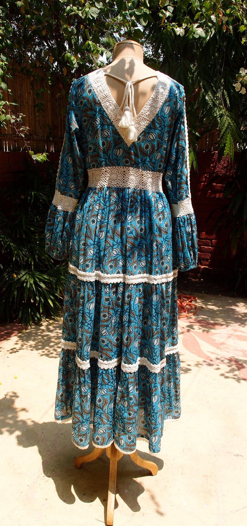 Pode incluir: Um vestido maxi floral azul e branco com acabamento em croch&ecirc; e um la&ccedil;o de borla nas costas.