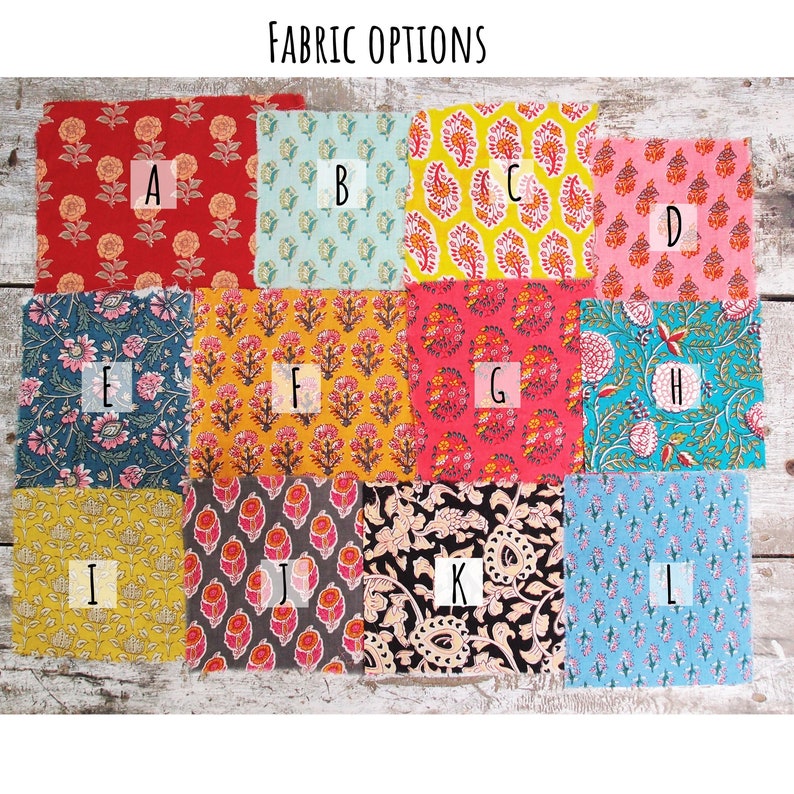 Pode incluir: Amostras de tecido em uma variedade de cores e padr&otilde;es, etiquetados de A a L. As amostras est&atilde;o dispostas em uma grade sobre uma superf&iacute;cie de madeira.  FABRIC OPTIONS est&aacute; escrito na parte superior da imagem.