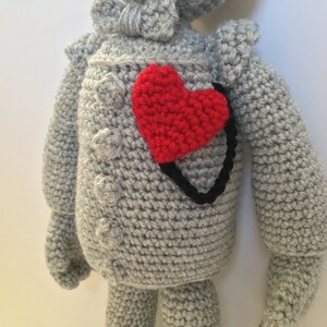 Op de afbeelding: Een grijs gehaakt knuffeldier van de Tin Man uit The Wizard of Oz. Het speelgoed heeft een rood hart op zijn borst genaaid.