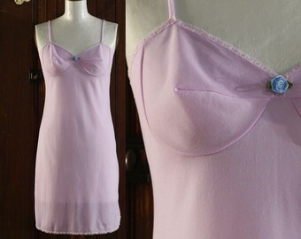 May include: A light purple slip dress with a lace trim and a small blue flower accent on the bust.