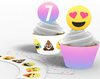 May include: Two cupcakes decorated with emoji toppers. One cupcake has a pink and blue ombre cupcake liner with a yellow emoji with hearts for eyes. The other cupcake has a white cupcake liner with a yellow emoji laughing with tears and a brown emoji poop. Both cupcakes have white frosting and a round topper with the number 7 on it.