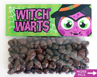 Op de afbeelding: Een doorzichtige plastic zak gevuld met chocolade bedekte rozijnen. De zak heeft een groen en paars label met de tekst "Witch Warts" met een cartoonheks met paarse huid en groene ogen.