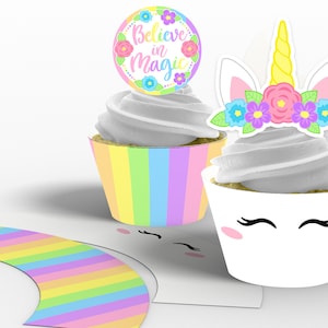 Op de afbeelding: Eénhoorn cupcake-verpakkingen met een regenboogstrepenpatroon en een eenhoorn gezicht met wimpers. De cupcake-topper is een cirkel met de tekst "Believe in Magic" en een bloemenkrans.