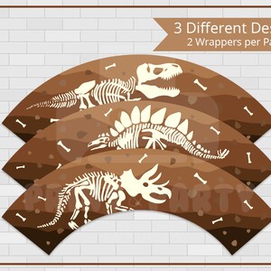 May include: Three cupcake wrappers with dinosaur skeleton designs. The wrappers are brown with a textured background and white dinosaur skeletons. The text "3 Different Designs 2 Wrappers per Page" is at the top of the image.