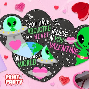 May include: Three printable Valentine's Day cards featuring a green alien with a spaceship. The cards are shaped like hearts and have a black background with white stars. The text on the cards reads: "You have abducted my heart", "Believe in you Valentine", and "Out of this world".