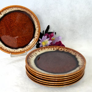 May include: Set of six brown and white glazed ceramic dessert plates. The plates have a brown center with a white rim.