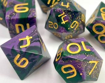 Può includere: Un set di sette dadi poliedrici nei toni del verde e del viola con numeri dorati. I dadi sono progettati per giochi di ruolo da tavolo. I dadi sono fatti di un materiale traslucido con glitter dorati.