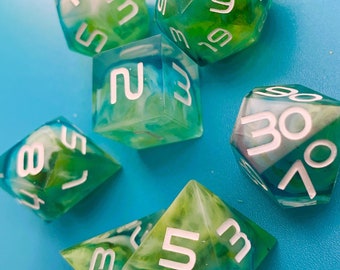 May include: A set of six green and white dice with white numbers. The dice are made of clear resin with a swirling green and white pattern.
