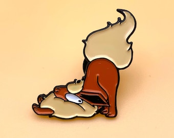 Può includere: Uno spillo in smalto marrone e arancione con una volpe di cartone animato rannicchiata con una volpe più piccola. Lo spillo ha un design carino e fantasioso.