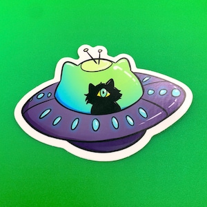 May include: A black cat with one large eye sits inside a purple and green flying saucer with a white outline.