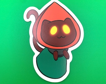 May include: A sticker featuring a cartoon cat wearing a red hooded cloak. The cat has brown fur and glowing yellow eyes. The cat is standing on a green background.