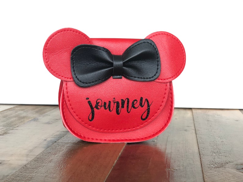 May include: Red faux leather purse with black bow and the word "journey" in black glitter lettering.