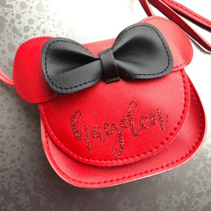 May include: Red faux leather purse with a black bow and the name "Grayson" embroidered in red glitter.