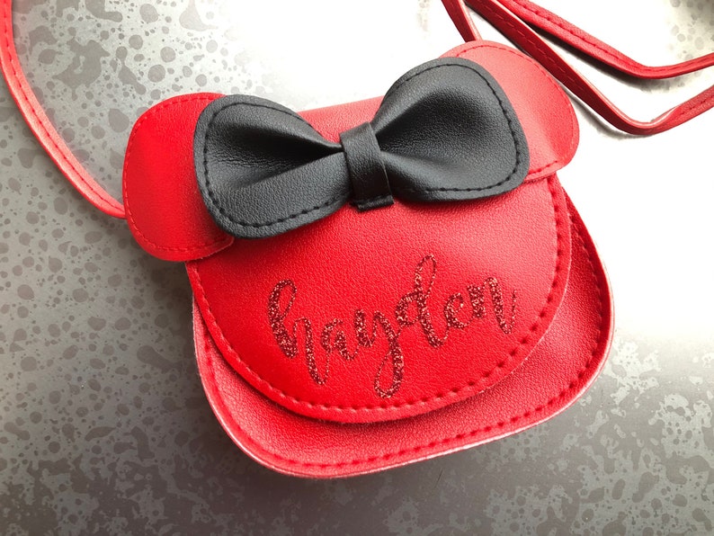 May include: Red faux leather purse with a black bow and the name "Grayson" embroidered in red glitter.