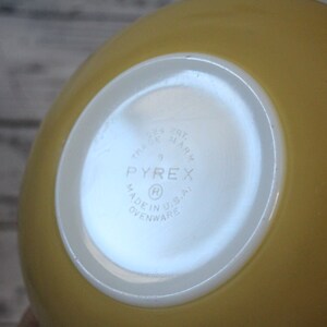 May include: Yellow Pyrex mixing bowl with a white bottom. The bottom has the Pyrex logo and the text "Trade Mark", "9", "Made in U.S.A.", and "Ovenware".