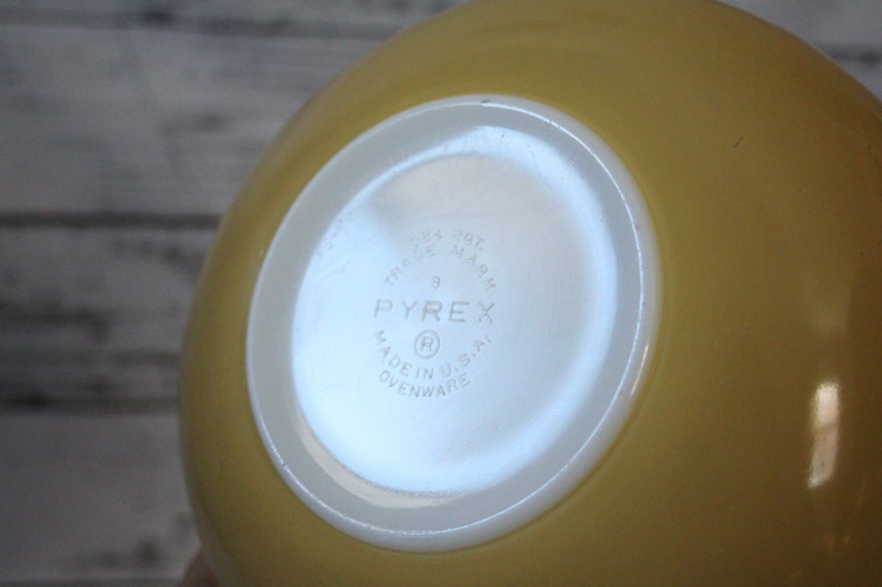 May include: Yellow Pyrex mixing bowl with a white bottom. The bottom has the Pyrex logo and the text "Trade Mark", "9", "Made in U.S.A.", and "Ovenware".