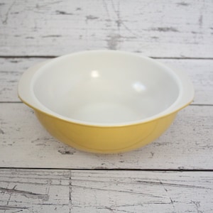 May include: A yellow mixing bowl with white interior. The bowl has two handles on the sides.