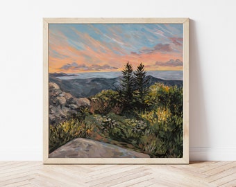 May include: A painting of a mountain landscape with two pine trees in the foreground. The sky is a vibrant blue with pink and orange clouds. The mountains are a dark blue and green. The painting is framed in a light wood frame.