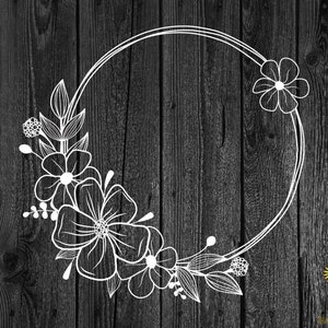 May include: A white floral wreath with a circular frame. The wreath is made of stylized flowers and leaves. The wreath is on a dark wood background.