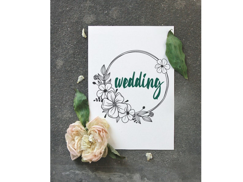 May include: A white card with a black floral wreath and the word "wedding" written in teal green.