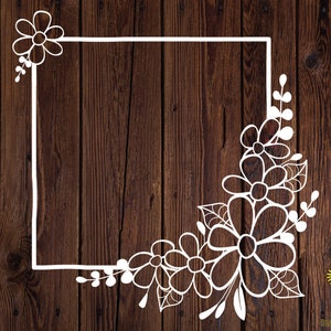 May include: A white floral design with a square frame on a brown wood background. The design includes a cluster of flowers in the bottom right corner and a single flower in the top left corner.