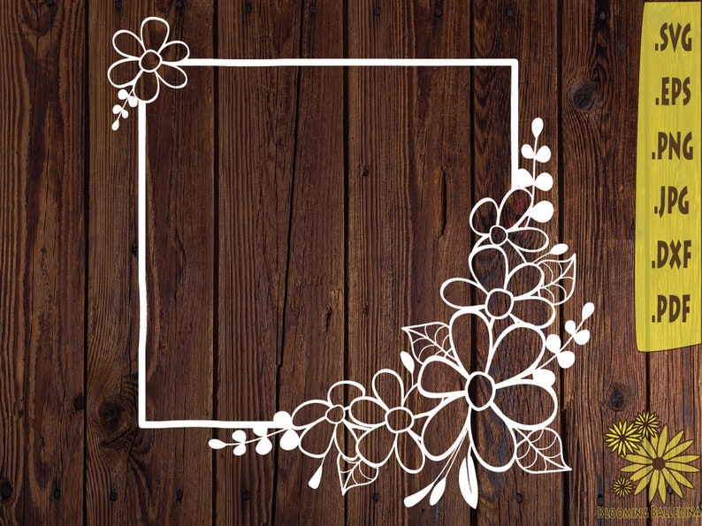 May include: A white floral design with a square frame on a brown wood background. The design includes a cluster of flowers in the bottom right corner and a single flower in the top left corner.