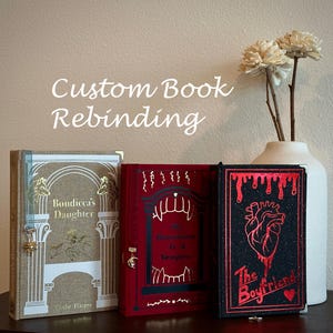May include: Three hardcover books with custom covers. The left book is tan with white architectural details and wolf motifs. The center book is red with white fangs and text. The right book is black with a red anatomical heart and dripping text.