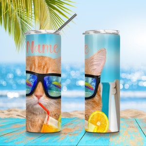 May include: A stainless steel tumbler with a personalised name, featuring a cartoon orange cat wearing sunglasses and drinking a beverage with a straw. The cat is sitting on a beach chair with a beach background.