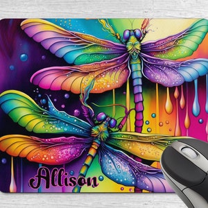 May include: A colourful mouse mat featuring a design of two iridescent dragonflies with dripping paint and the name "Allison" in pink cursive.