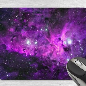 May include: Purple and black galaxy themed mouse mat with a black computer mouse on top of it.