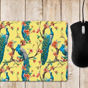 May include: A yellow mouse mat with a repeating pattern of peacocks and pink flowers. The peacocks have blue and green feathers.