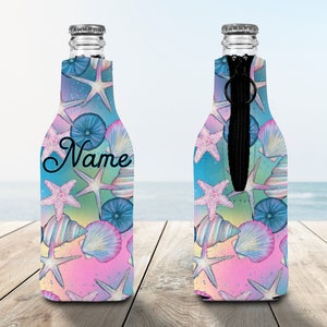 May include: A personalised bottle cooler with a zipper closure. The cooler features a colourful design of seashells, starfish, and sea urchins on a blue, pink, and green background. The text "Name" is printed on the cooler.