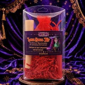 May include: A clear plastic box containing a Love Spell Kit with a red organza bag, a rolled parchment scroll, a red candle, and red shredded paper filler. The label features the text Love Spell Kit, For Positive Relationships and Increased Attraction.