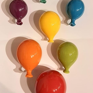 Può includere: Sei ornamenti di palloncino in ceramica di vari colori, tra cui verde, viola, giallo, arancione, verde e rosso. I palloncini sono lucidi e hanno una forma di palloncino realistica.