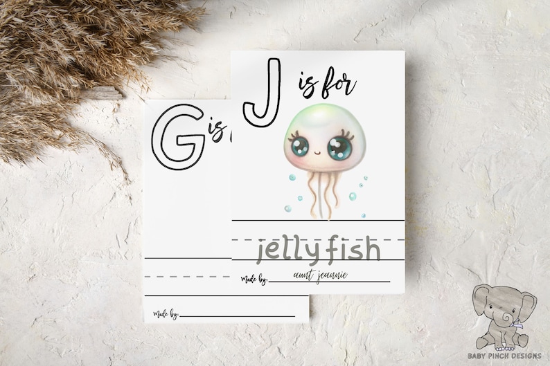 Blank baby shower coloring pages G and J. Letter J page shows a sample drawing of a jellyfish and is signed by a guest