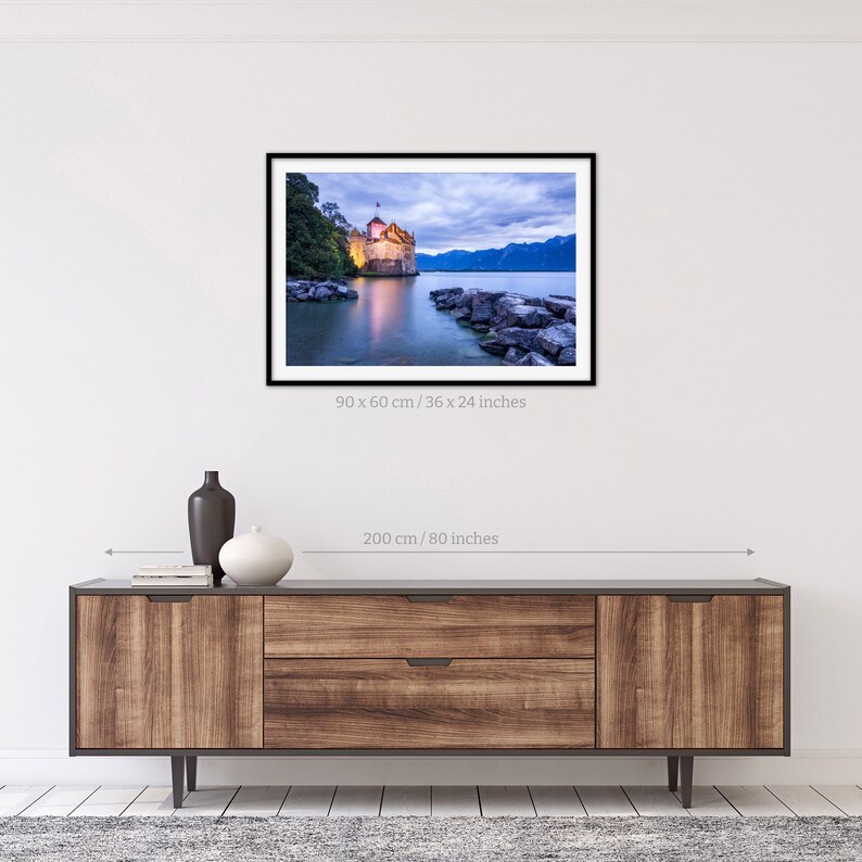 May include: A photograph of a castle on a lake at dusk. The castle is lit up and the water is calm. The sky is a soft blue and purple. The image is 36 x 24 inches.