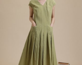 May include: A light green linen dress with a v-neck, short sleeves, and a pleated skirt. The dress has two pockets on the front.
