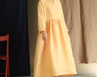 May include: A long-sleeved, light yellow linen dress with a v-neckline and a gathered skirt.
