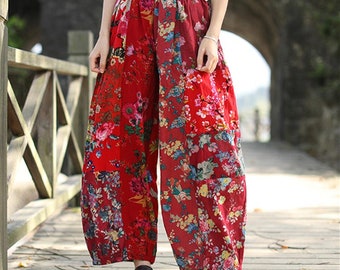 May include: Red wide-leg pants with a floral patchwork design. The pants have an elastic waistband and a relaxed fit.