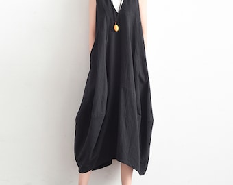 May include: A black sleeveless maxi dress with a V-neckline and a loose, flowing silhouette. The dress has a simple design with pockets on the sides and a slightly asymmetrical hemline.