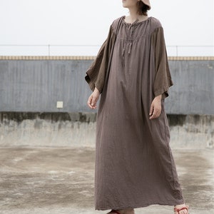 May include: A long, brown, loose-fitting dress with a gathered neckline and long sleeves. The sleeves are a darker brown color than the dress. The dress is made of a soft, flowing fabric.