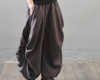 May include: A pair of loose-fitting, dark gray linen pants with a gathered, draped design. The pants have a wide leg and a relaxed fit.